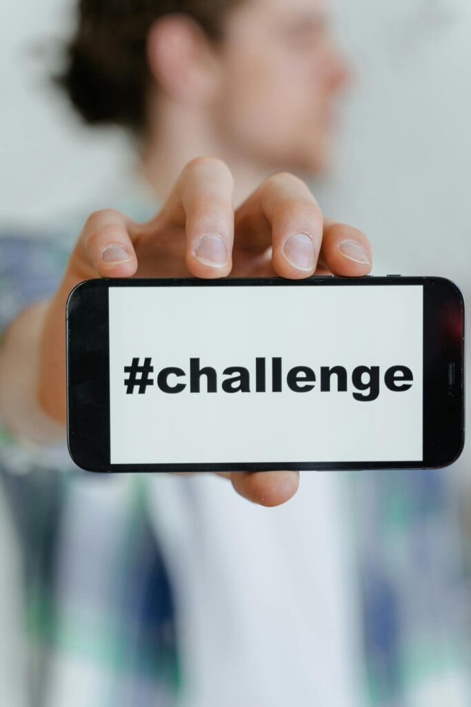 Close-up of a person holding a smartphone displaying #challenge.